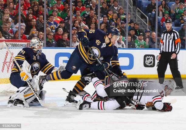 Brendan Guhle of the Buffalo Sabres upends Tomas Jurco of the Chicago Blackhawks in front of Chad Johnson during an NHL game on March 17, 2018 at...