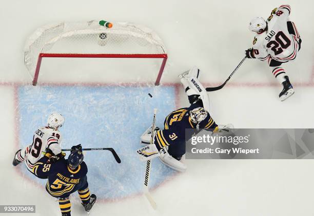 Chad Johnson of the Buffalo Sabres defends against Brandon Saad and Jonathan Toews of the Chicago Blackhawks during an NHL game on March 17, 2018 at...