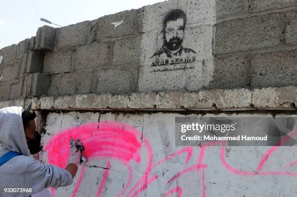 Yemeni artist writes the word "PEACE" on a wall under a picture of the Houthi 1-leader Housin al-Houthi, during an Open Day of graffiti campaign call...