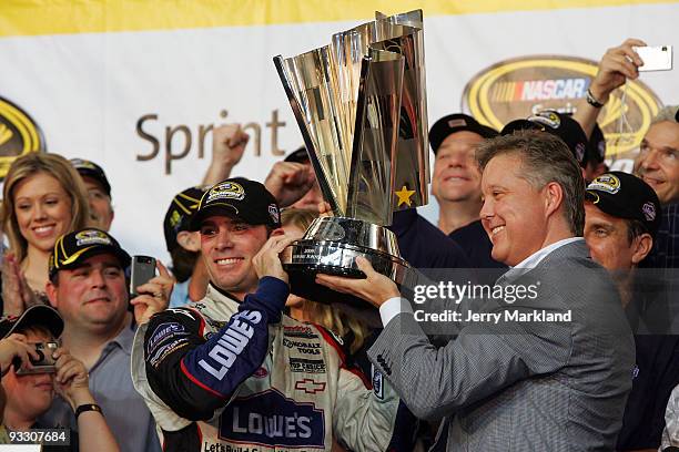 Jimmie Johnson , driver of the Lowe's Chevrolet, and NASCAR Chairman and CEO Brian France hoist the trophy after winning the NASCAR Sprint Cup Series...