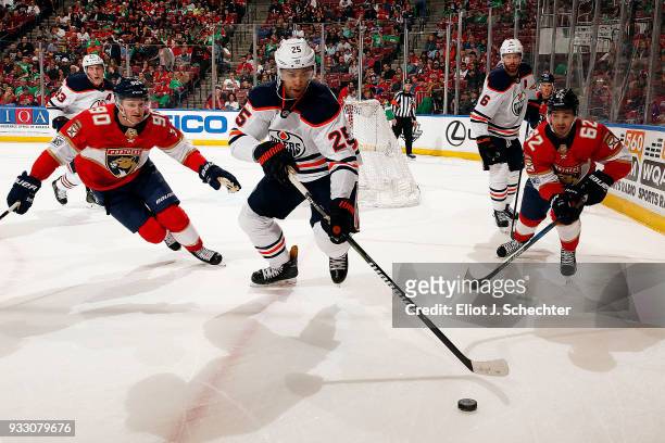 Darnell Nurse of the Edmonton Oilers skates for possession against Jared McCann and teammate Denis Malgin of the Florida Panthers at the BB&T Center...