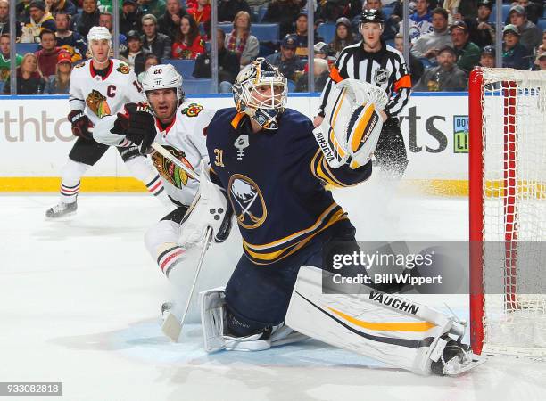 Chad Johnson of the Buffalo Sabres makes a glove save as Brandon Saad of the Chicago Blackhawks looks for a rebound during an NHL game on March 17,...