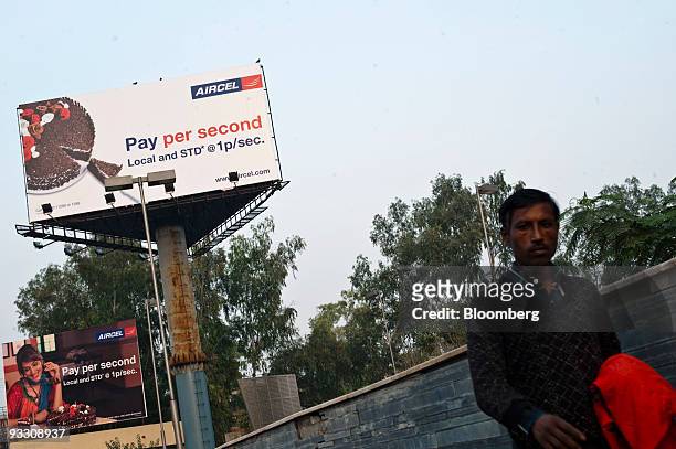 Man walks under a billboard advertising reduced rates for the mobile phone provider Aircel Ltd. In Noida, India, on Sunday, Nov. 22, 2009. India's 11...