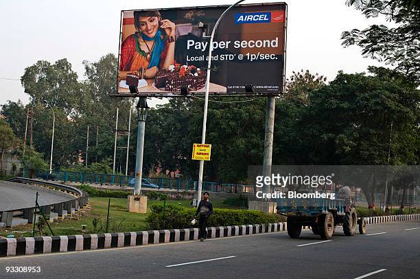 Man walks under a billboard advertising reduced rates for the mobile phone provider Aircel Ltd. In Noida, India, on Sunday, Nov. 22, 2009. India's 11...