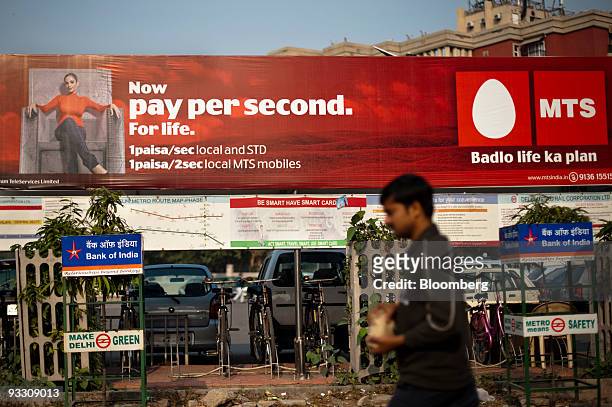 Man walks under a billboard advertising reduced rates for the mobile phone provider MTS, a brand of Sistema Shyam TeleServices Ltd., in New Delhi,...