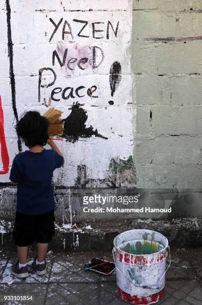 Yemeni child draws as he takes part in an Open Day of graffiti campaign call for peace on March 15, 2018 in Sana'a, Yemen.
