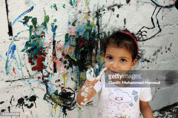 Yemeni little girl shows her paintbrush as she participates in an Open Day of graffiti campaign call for peace on March 15, 2018 in Sana'a, Yemen.