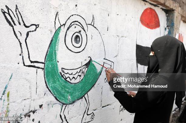 Yemeni woman draws graffiti during an Open Day of graffiti campaign call for peace on March 15, 2018 in Sana'a, Yemen.