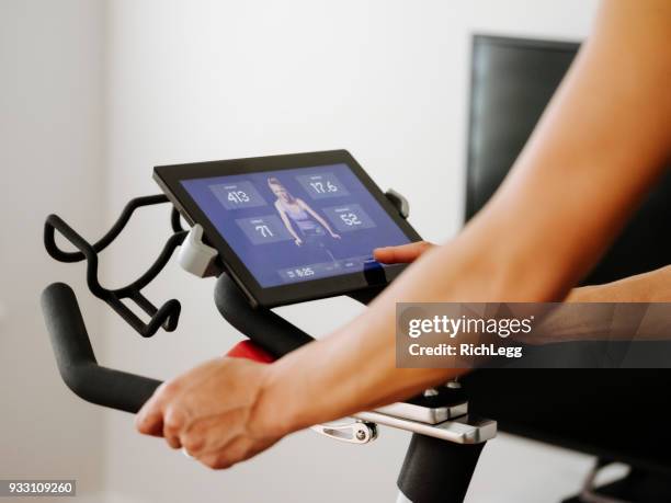 woman exercising on spin bike in home - bike ipad stock pictures, royalty-free photos & images