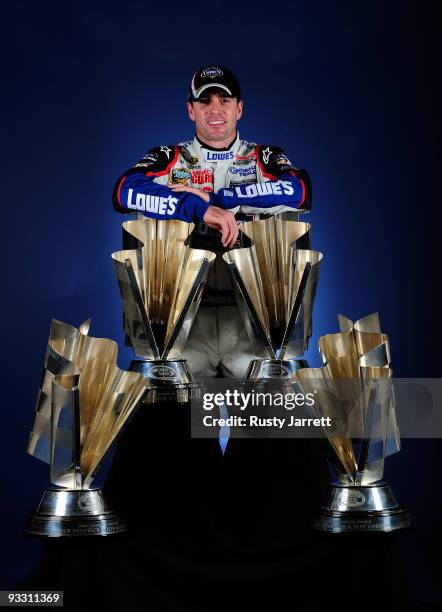 Jimmie Johnson, driver of the Lowe's Chevrolet, poses with all four of his championship trophies after winning the NASCAR Sprint Cup Series...