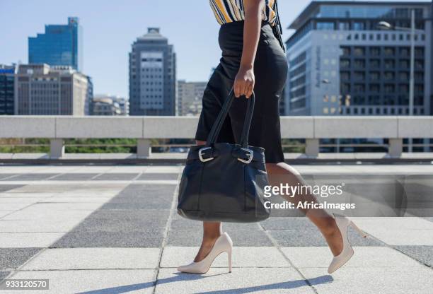 zakenvrouw op hoge hakken lopen door de stad met haar portemonnee in de hand. - african cityscape stockfoto's en -beelden