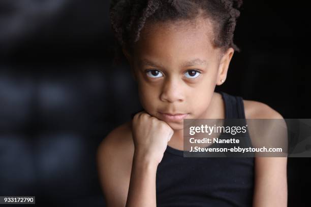 little girl looking at camera on dark background - nanette j stevenson ストックフォトと画像