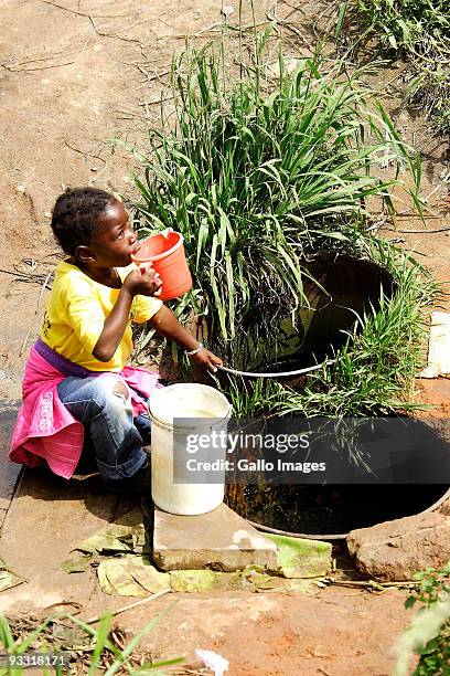 Child drinks water from a well at the Matsafeni community, in the shadow of the Mbombela Stadium on November 3, 2009 in Nelspruit, South Africa. The...