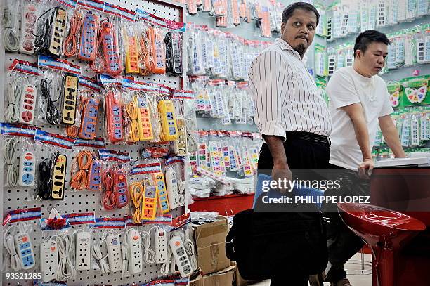 China-economy-trade-Mideast,FEATURE" by D'Arcy Doran In this picture taken on October 21 a buyer looks on as he stands in a shop selling power plugs...