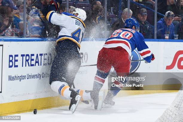 Robert Bortuzzo of the St. Louis Blues skates into the boards as he goes after the puck with Chris Kreider of the New York Rangers at Scottrade...