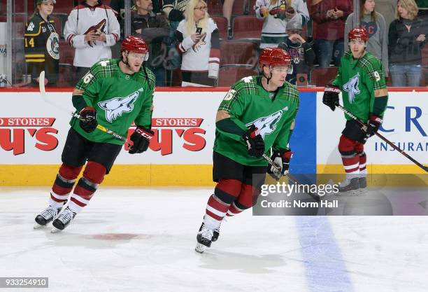 Christian Fischer and Max Domi of the Arizona Coyotes wear special green warm up jerseys in recognition of St. Patrick's Day prior to a game against...