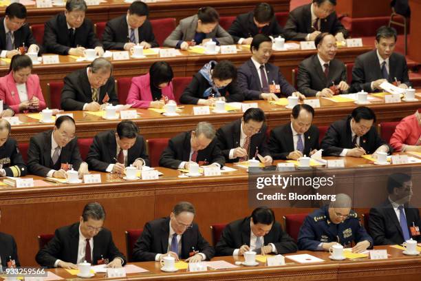 Delegates fill in their ballots during a vote at a session at the first session of the 13th National People's Congress at the Great Hall of the...