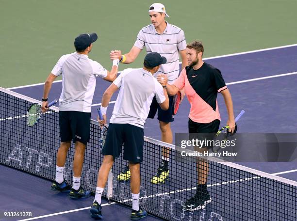 John Isner and Jack Sock of the United States shake hands with Bob Bryan and Mike Bryan of the United States after beating them in the ATP doubles...