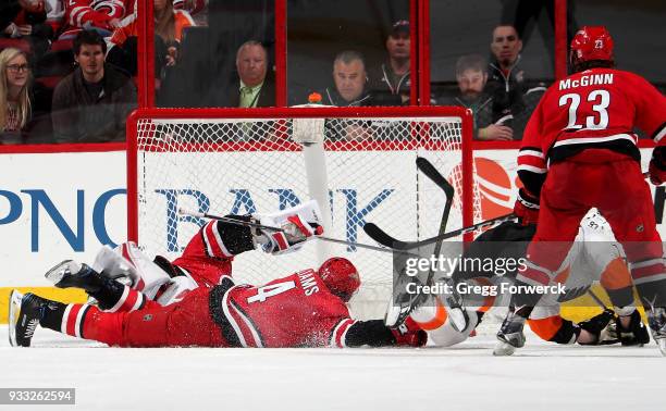 Jakub Voracek of the Philadelphia Flyers backhands the puck past the defense of Justin Williams of the Carolina Hurricanes and teammate goaltender...