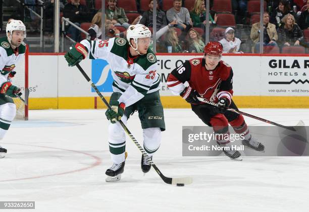 Jonas Brodin of the Minnesota Wild advances the puck up ice ahead of Max Domi of the Arizona Coyotes during the first period at Gila River Arena on...