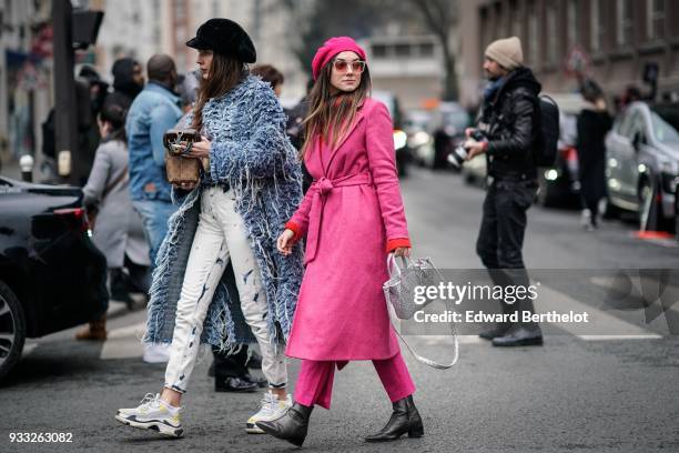 Guest wears a black cap, a glossy blue fringe coat, a brown patterned bag, white pants with black pattern , white sneakers ; a guest wears a fuchsia...