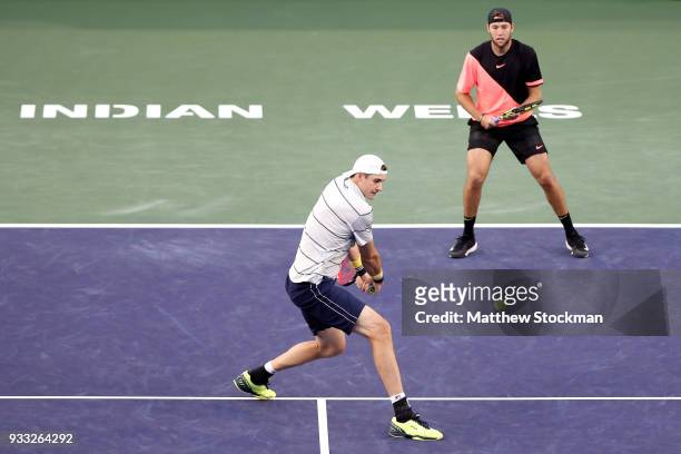 John Isner returns a shot to Mike Bryan and Bob Bryan while playing with Jack Sock during the men's doubles final on Day 13 of the BNP Paribas Open...