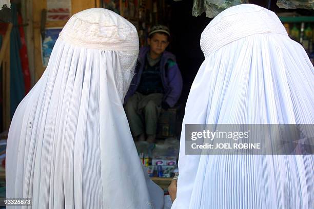 Two women wearing the traditional burqas buy goods at the village bazaar 07 November 2001 in Dasht-E-Qaleh, in northeastern Afghanistan. AFP PHOTO...