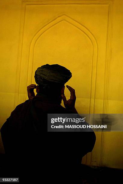 An Afghan man prays during a prayer service for the victims of the 06 November suicide blast at the Eid Gah mosque in Kabul, 09 November 2007. A...