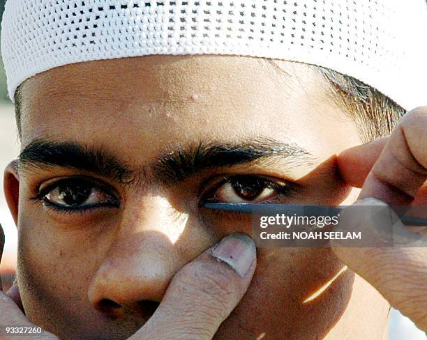 An Indian Muslim applies Surma to his eyes before entering the Mosque to offer prayers on the occassion of the Eid al-Adha festival festival in...