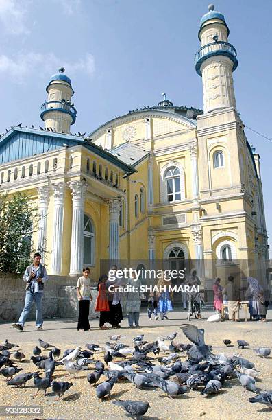 Afghan women feed seeds to pigeons infront of a Shah-Do-Shamshira Shrine in Kabul, 25 August 2004. The name of the Shrine, meaning the Mosque of the...