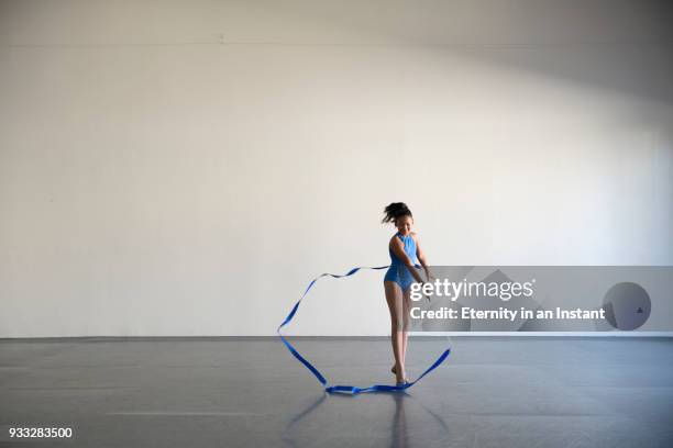 mixed race girl dancing in a gymnasium with a ribbon - ribbon dance stock pictures, royalty-free photos & images