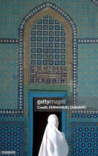 An Afghan woman walks in front of a blue ceramic-tiled wall at Mazar-i-Sharif Blue Mosque, 03 October 2004. Afghanistan is set to hold its first ever...
