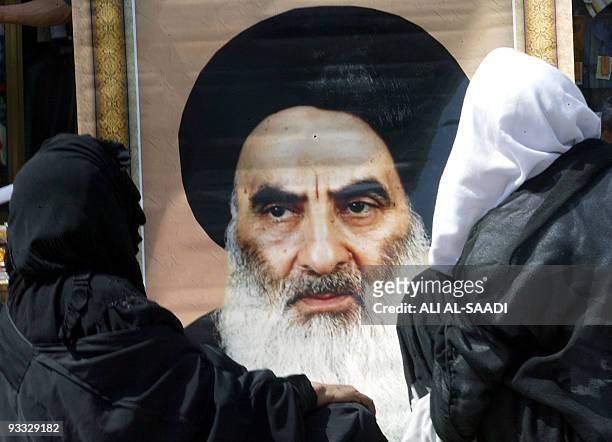 Two women sit in a cart as a man tries to sell them a large poster of Grand Ayatollah Ali Sistani, in the Kazemiya neighborhood of Baghdad 19 May...