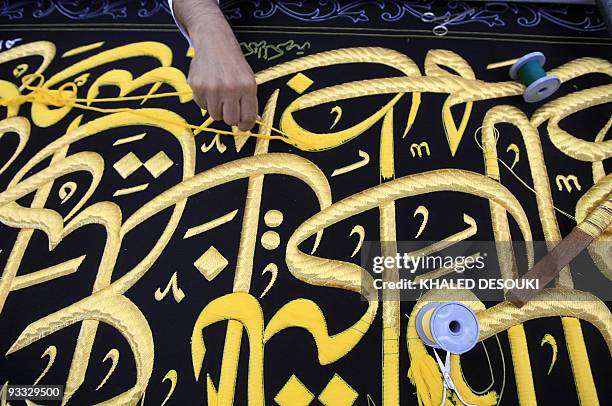 Saudi worker sews Islamic calligraphy in gold thread on a drape to cover the Kaaba at the Kiswa factory in the holy city of Mecca on November 29,...