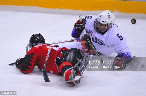 Billy Hanning and Canada's Greg Westlake fight for the puck in the ice hockey gold medal game between Canada and the US at the Gangneung Hockey...
