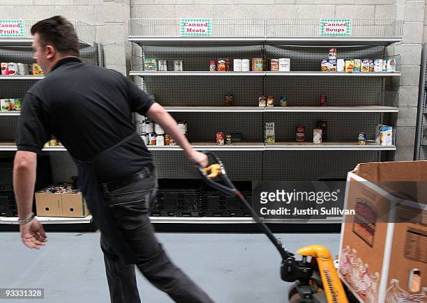 Worker pulls a pallet jack by a nearly empty shelf in the warehouse at the San Francisco Food Bank November 23, 2009 in San Francisco, California. As...