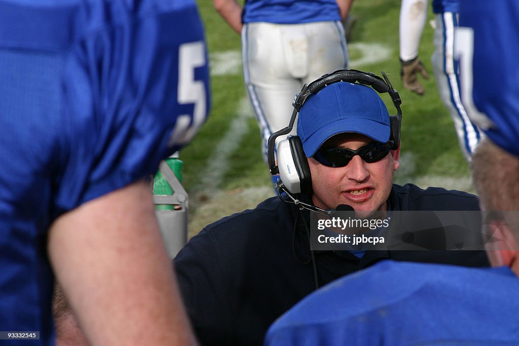 Close-up of football coach talking to team in the huddle