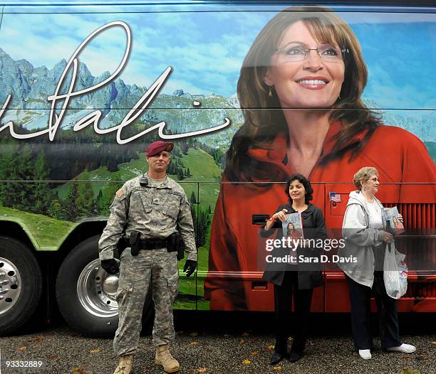 An 82nd Airborne Military Police Officer guards the tour bus of former Alaska Gov. Sarah Palin as people have their photos taken with their signed...