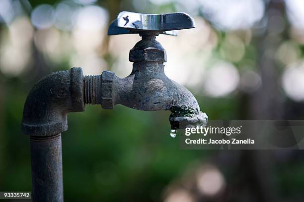 water drop falling from faucet - tap stockfoto's en -beelden