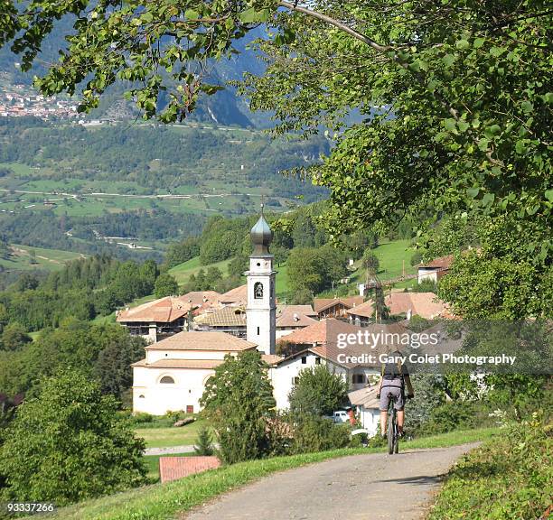 rural cyclist in village in dolomites - gary colet stock pictures, royalty-free photos & images