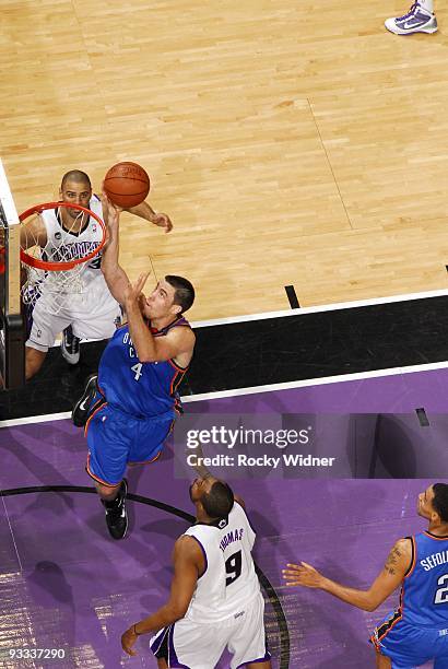 Nick Collison of the Oklahoma City Thunder shoots a layup against Kenny Thomas of the Sacramento Kings during the game at Arco Arena on November 10,...