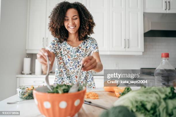 vrouw mengen een salade in de keuken - woman salad stockfoto's en -beelden