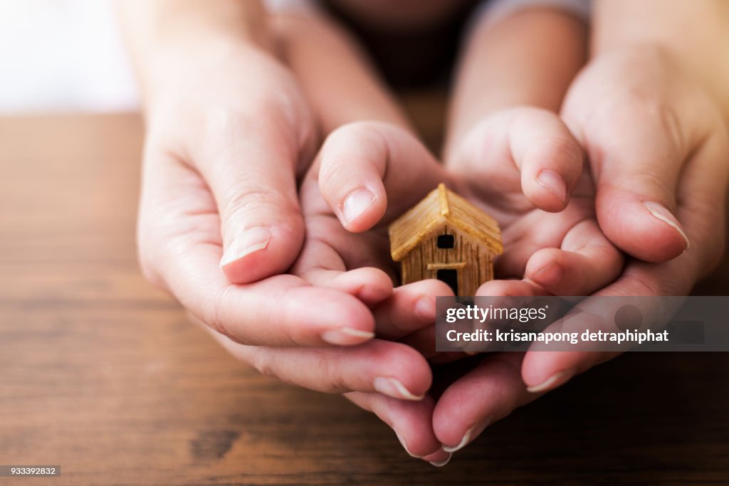 Home concept,people, family and home concept - close up of woman and girl holding model house