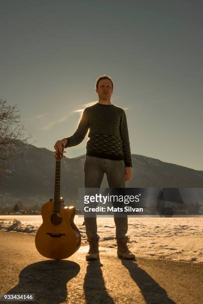 musician man holding his guitar on a street with sunlight - low angle view street stock-fotos und bilder