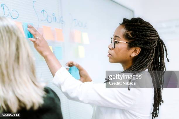 young businesswoman writing notes on board in office - quadro transparente imagens e fotografias de stock