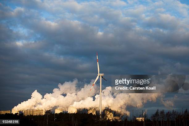 Loan wind turbine spins as exhaust plumes from cooling towers at the Jaenschwalde lignite coal-fired power station, which is owned by Vatenfall, on...
