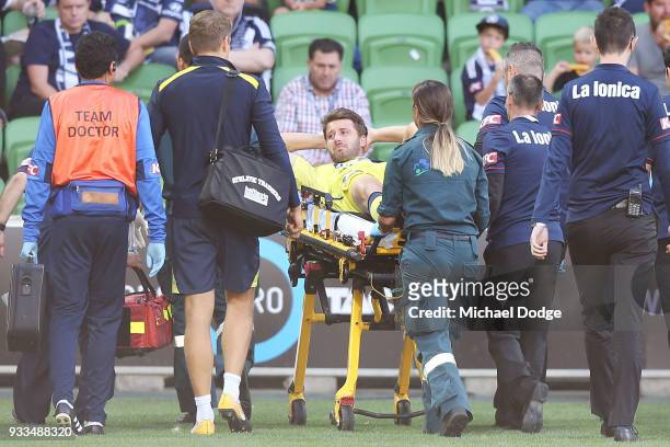 Anthony Golec of the Mariners reacts in pain after he crashes into Victory goalkeeper Lawrence Thomas in a contest and was later carried off on a...