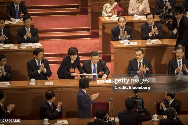 An attendant hands Xi Jinping, China's president, center, a document during a session at the first session of the 13th National People's Congress at...