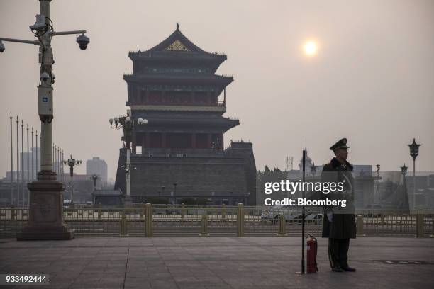 Member of the Chinese People's Armed Police stands guard next to a fire extinguisher in Tiananmen Square in Beijing, China, on Sunday, March 18,...