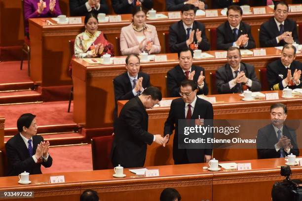 Chinese President Xi Jinping and Chinese Premier Li Keqiang shake hands as delegates applaud following the announcement of parliament approving Li's...